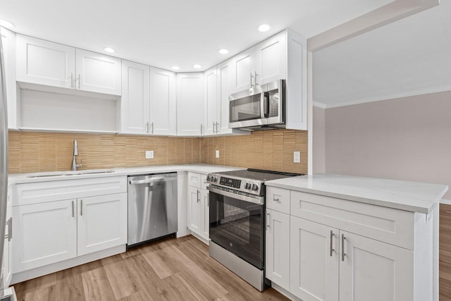 kitchen with a sink, stainless steel appliances, tasteful backsplash, crown molding, and white cabinetry