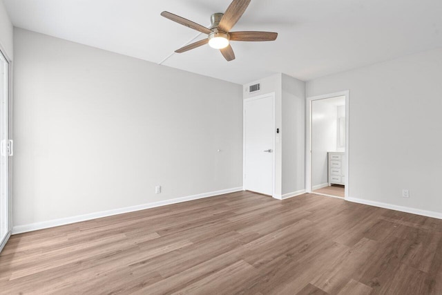 unfurnished bedroom with ensuite bathroom, visible vents, wood finished floors, and baseboards