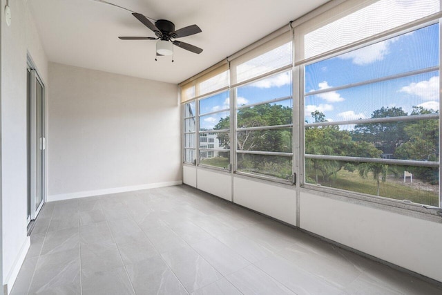 unfurnished sunroom with ceiling fan, baseboards, and tile patterned floors