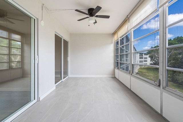 unfurnished sunroom featuring tile patterned floors, baseboards, and a ceiling fan