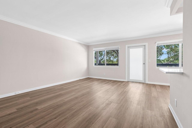 unfurnished living room with baseboards, a wealth of natural light, and wood finished floors