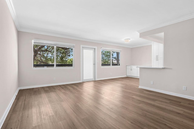 unfurnished living room with baseboards, ornamental molding, and wood finished floors