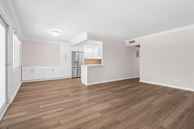 unfurnished living room featuring crown molding, baseboards, visible vents, and wood finished floors