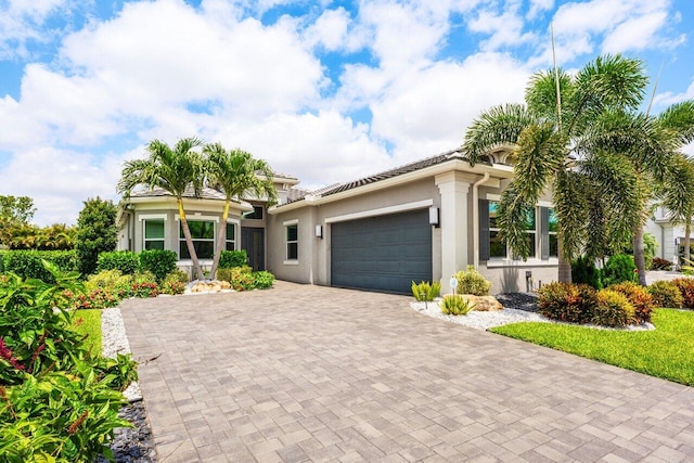 view of front of house with decorative driveway, an attached garage, and stucco siding
