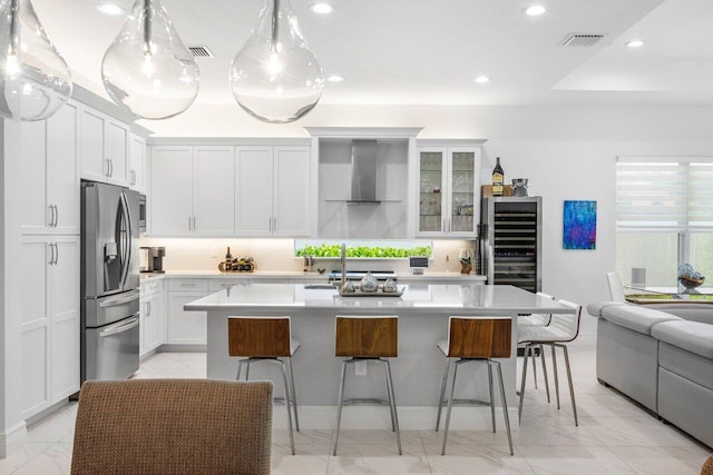 kitchen featuring wall chimney range hood, stainless steel refrigerator with ice dispenser, beverage cooler, and marble finish floor