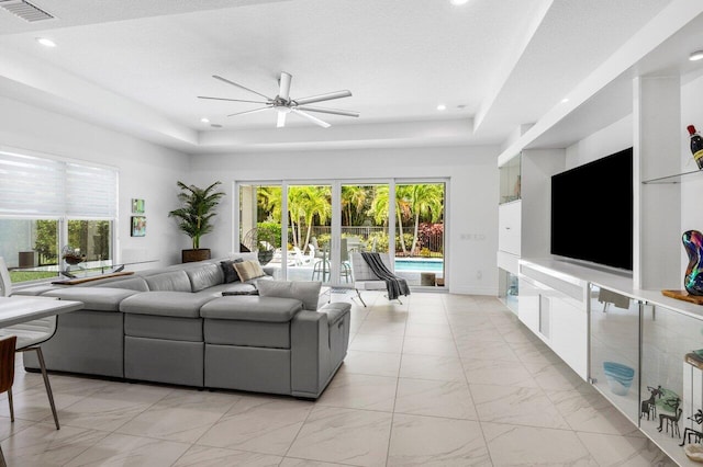 living room with visible vents, a raised ceiling, ceiling fan, and a wealth of natural light