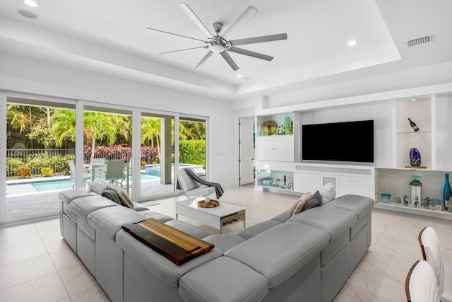 living room with plenty of natural light, a ceiling fan, marble finish floor, and visible vents