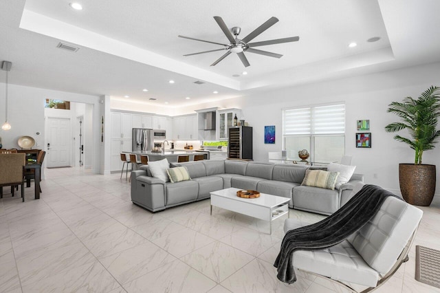 living area with visible vents, a ceiling fan, a raised ceiling, and recessed lighting