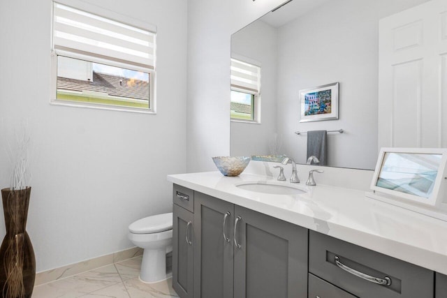 half bath with toilet, baseboards, marble finish floor, and vanity