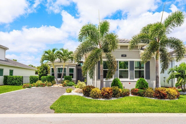 view of front of house with decorative driveway, stucco siding, and a front yard