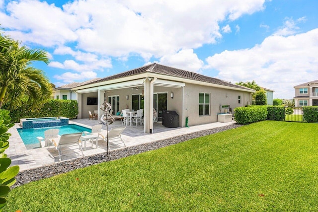back of house with ceiling fan, fence, stucco siding, a lawn, and a tile roof