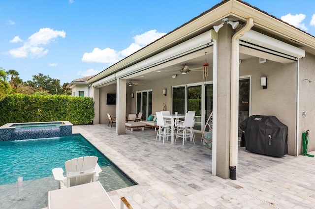 view of pool featuring outdoor dining space, a pool with connected hot tub, ceiling fan, grilling area, and a patio area