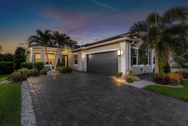 view of front of house with an attached garage, stucco siding, and decorative driveway