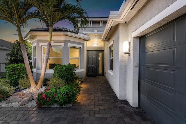 property entrance featuring a garage and stucco siding