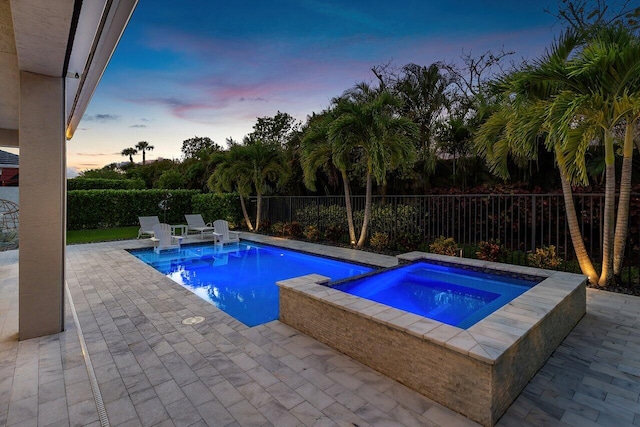 pool at dusk featuring a patio, a fenced backyard, an in ground hot tub, and a fenced in pool