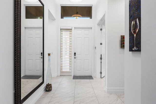 foyer with baseboards and marble finish floor