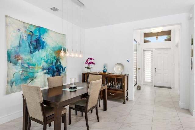dining area with baseboards, visible vents, and marble finish floor