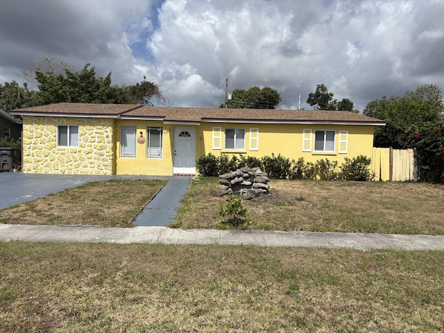 single story home with a front lawn, stucco siding, stone siding, and fence