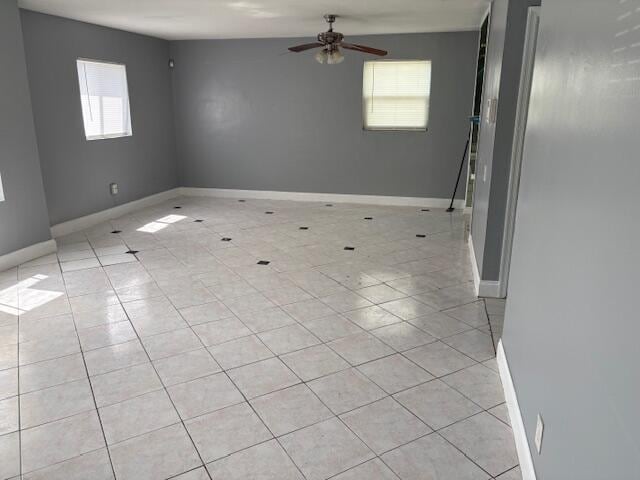 spare room with baseboards, ceiling fan, and light tile patterned floors