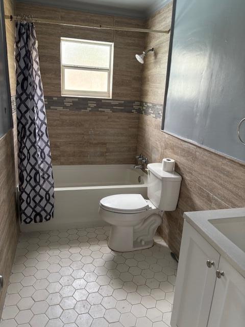 bathroom with toilet, tile walls, and shower / bath combo with shower curtain
