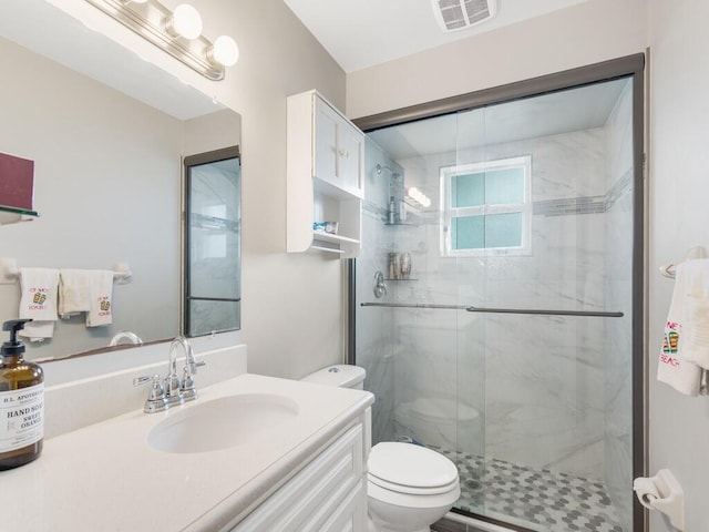 bathroom featuring toilet, visible vents, a marble finish shower, and vanity