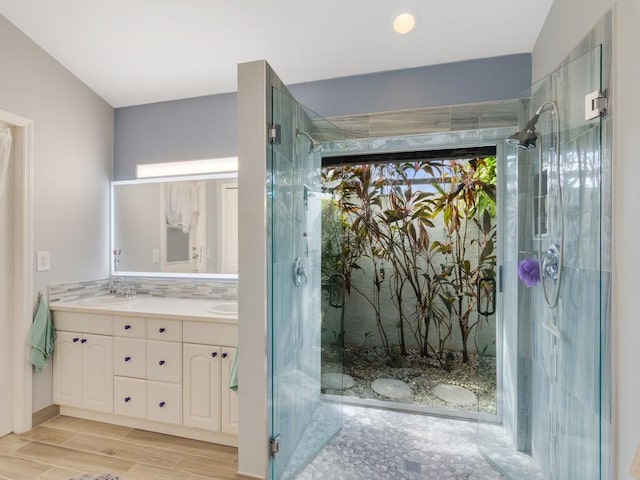 full bathroom featuring double vanity, a shower stall, a sink, and wood finished floors