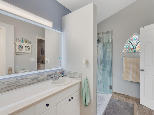 full bath with vanity, toilet, a shower stall, wood finished floors, and lofted ceiling