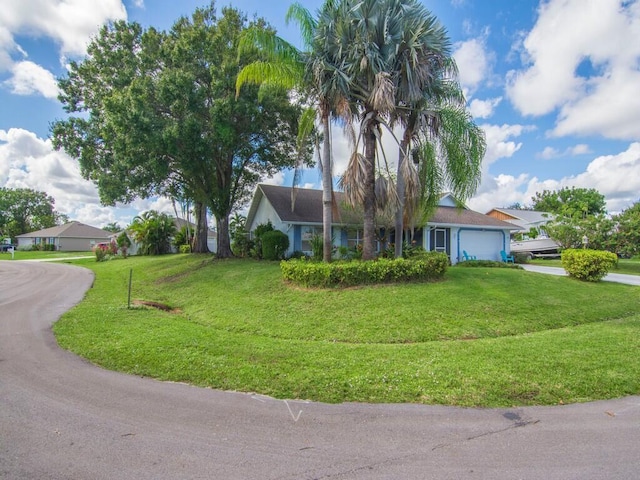 view of front of property featuring an attached garage, a front lawn, and driveway