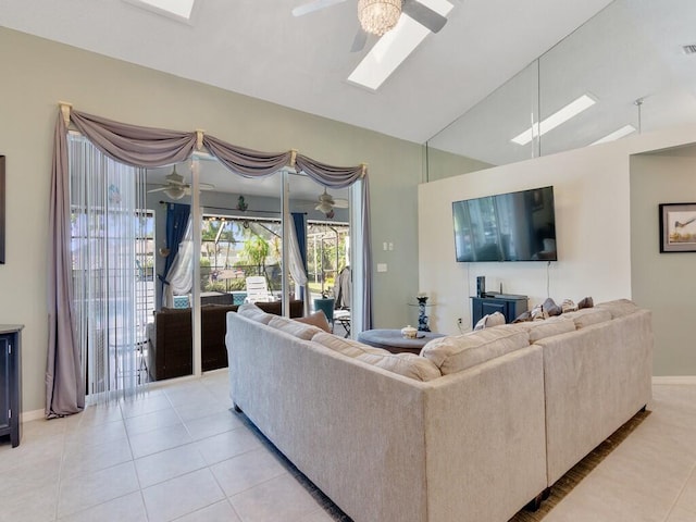 living area featuring visible vents, light tile patterned flooring, baseboards, lofted ceiling with skylight, and ceiling fan
