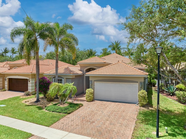 view of front of house with an attached garage, stucco siding, decorative driveway, and a front yard