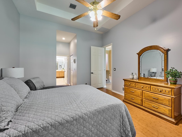 bedroom featuring visible vents, light wood-style flooring, ensuite bath, and baseboards