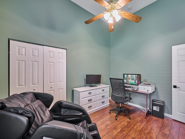 office space featuring baseboards, a high ceiling, a ceiling fan, and wood finished floors