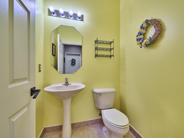 bathroom featuring baseboards, a sink, and toilet