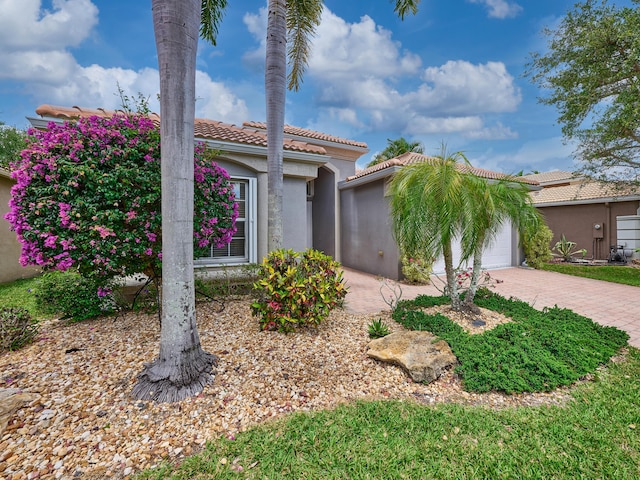 mediterranean / spanish-style home featuring decorative driveway, a garage, a tile roof, and stucco siding