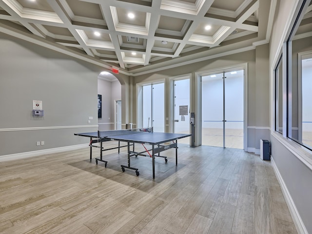 game room featuring arched walkways, beam ceiling, coffered ceiling, and light wood-style flooring