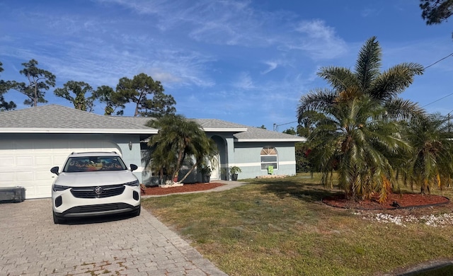 ranch-style home with a garage, decorative driveway, and a front lawn