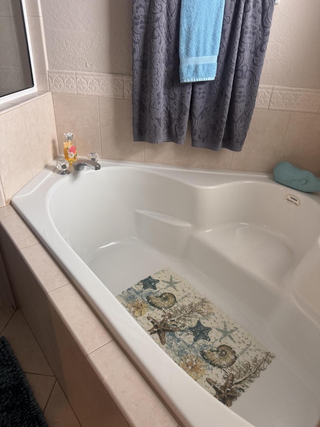 bathroom with a garden tub, a textured wall, and tile walls