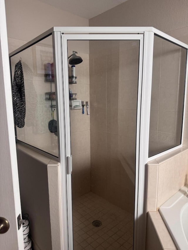 full bathroom featuring a shower stall and a bath