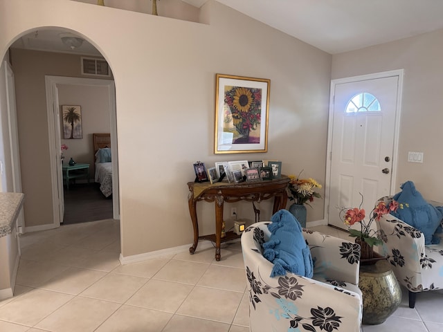 entryway featuring arched walkways, baseboards, light tile patterned flooring, and visible vents