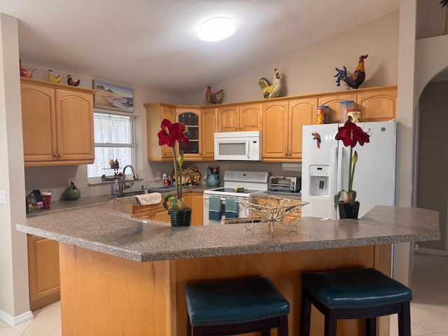 kitchen with a sink, arched walkways, light tile patterned floors, and white appliances