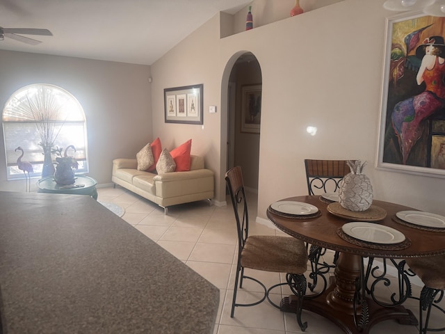 dining room with a ceiling fan, arched walkways, light tile patterned floors, and lofted ceiling