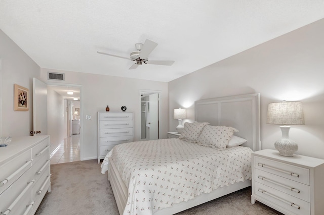 bedroom featuring a ceiling fan, visible vents, and light carpet