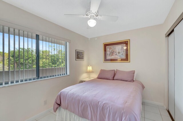 tiled bedroom featuring baseboards, ceiling fan, and a closet