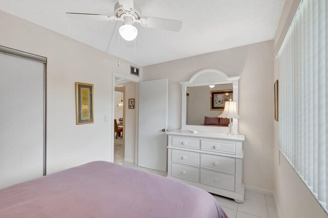 bedroom with ceiling fan, baseboards, light tile patterned floors, visible vents, and a closet