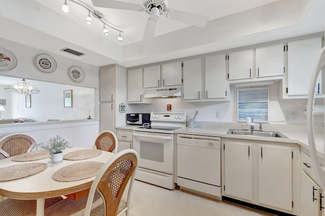 kitchen featuring a sink, white appliances, light countertops, under cabinet range hood, and visible vents