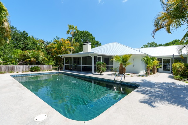view of swimming pool featuring a sunroom, fence, and a patio