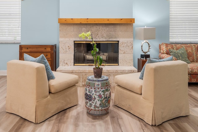 living room featuring wood finished floors, a tiled fireplace, and baseboards