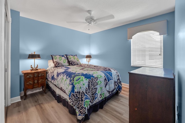 bedroom with light wood finished floors, baseboards, and a ceiling fan