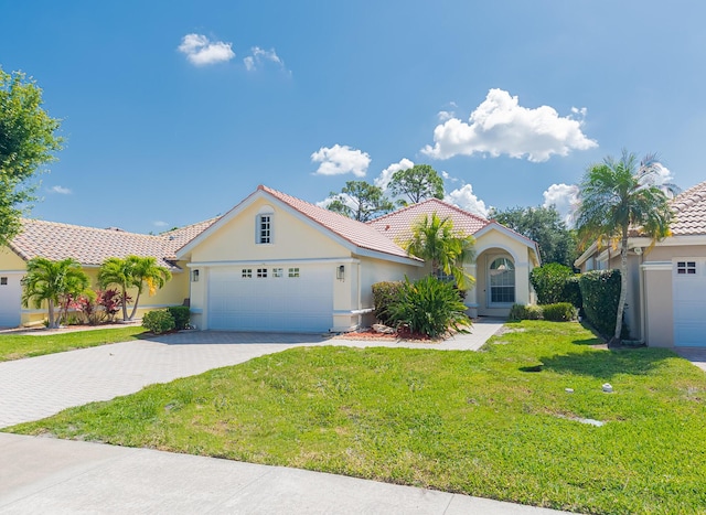 view of front facade featuring stucco siding, an attached garage, driveway, a front lawn, and a tiled roof