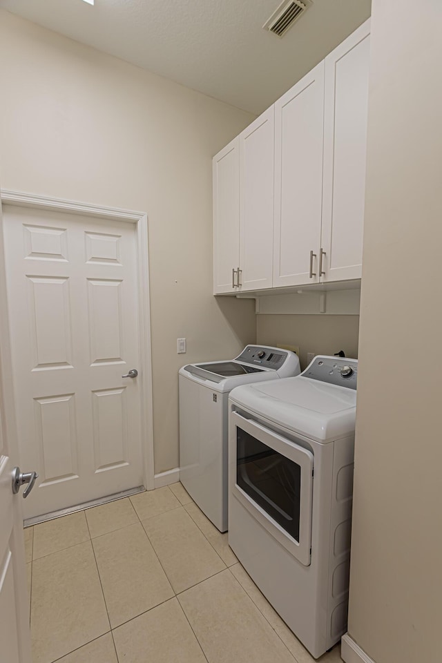 clothes washing area with light tile patterned floors, cabinet space, washing machine and clothes dryer, visible vents, and baseboards